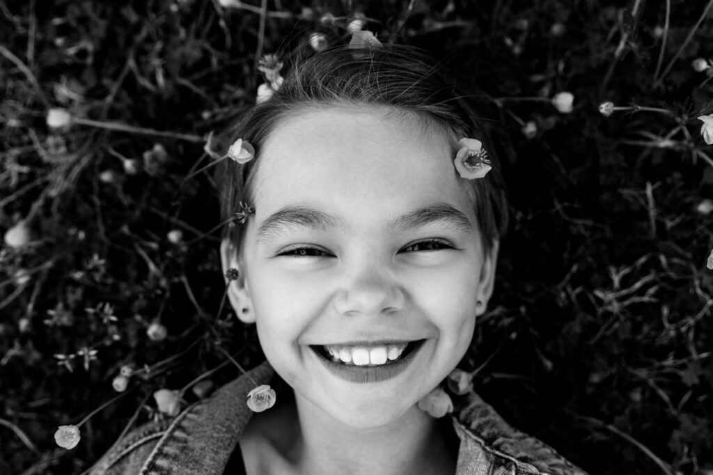Charming black and white portrait of a smiling child surrounded by nature.